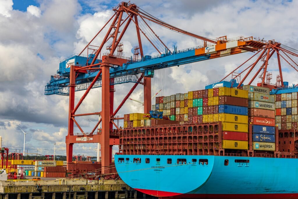 Ground-level view of a container ship docked at a destination port with cargo cranes
