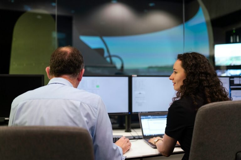 Two specialists comparing transport routes and operational data on multiple screens
